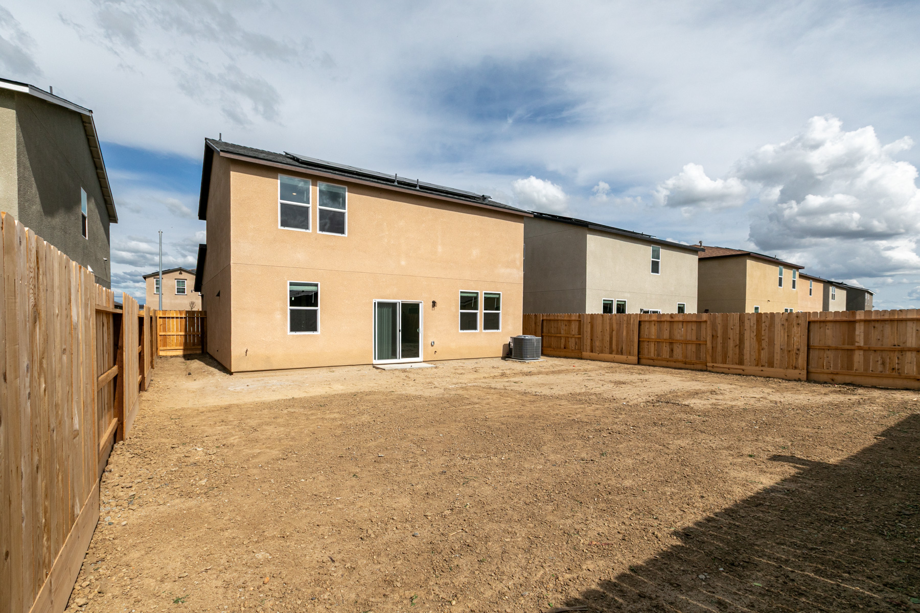 A dirt yard with a fence and a building in the background.