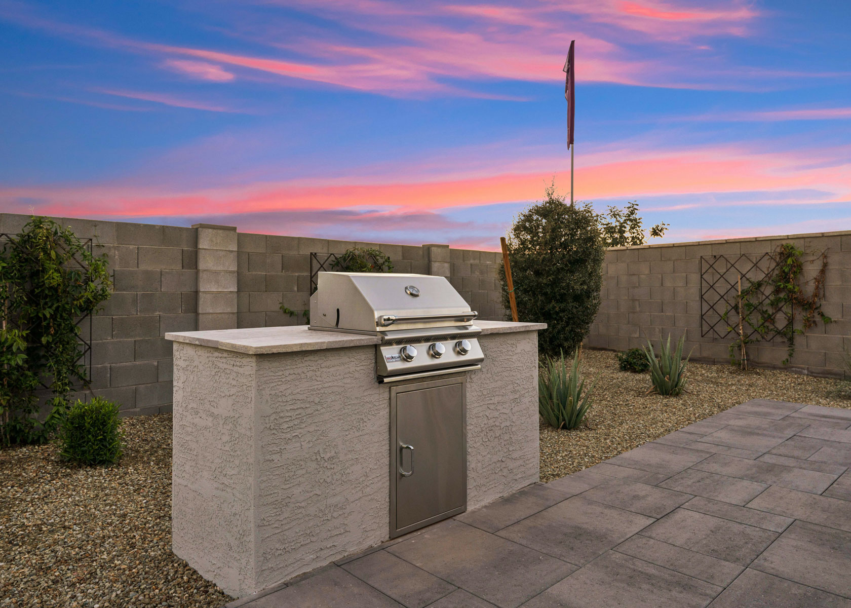 A couple of metal boxes on a stone surface with a brick wall and a pink sky.