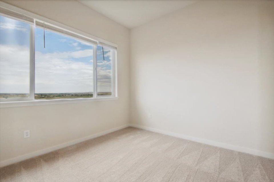 A room with a window and a white wall.