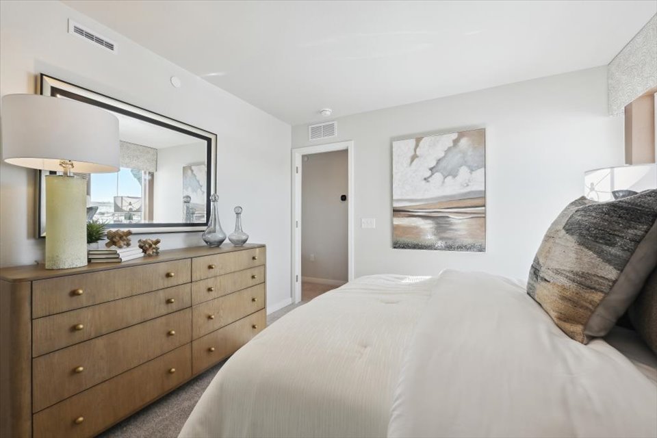 A bedroom with a bed and a mirror.