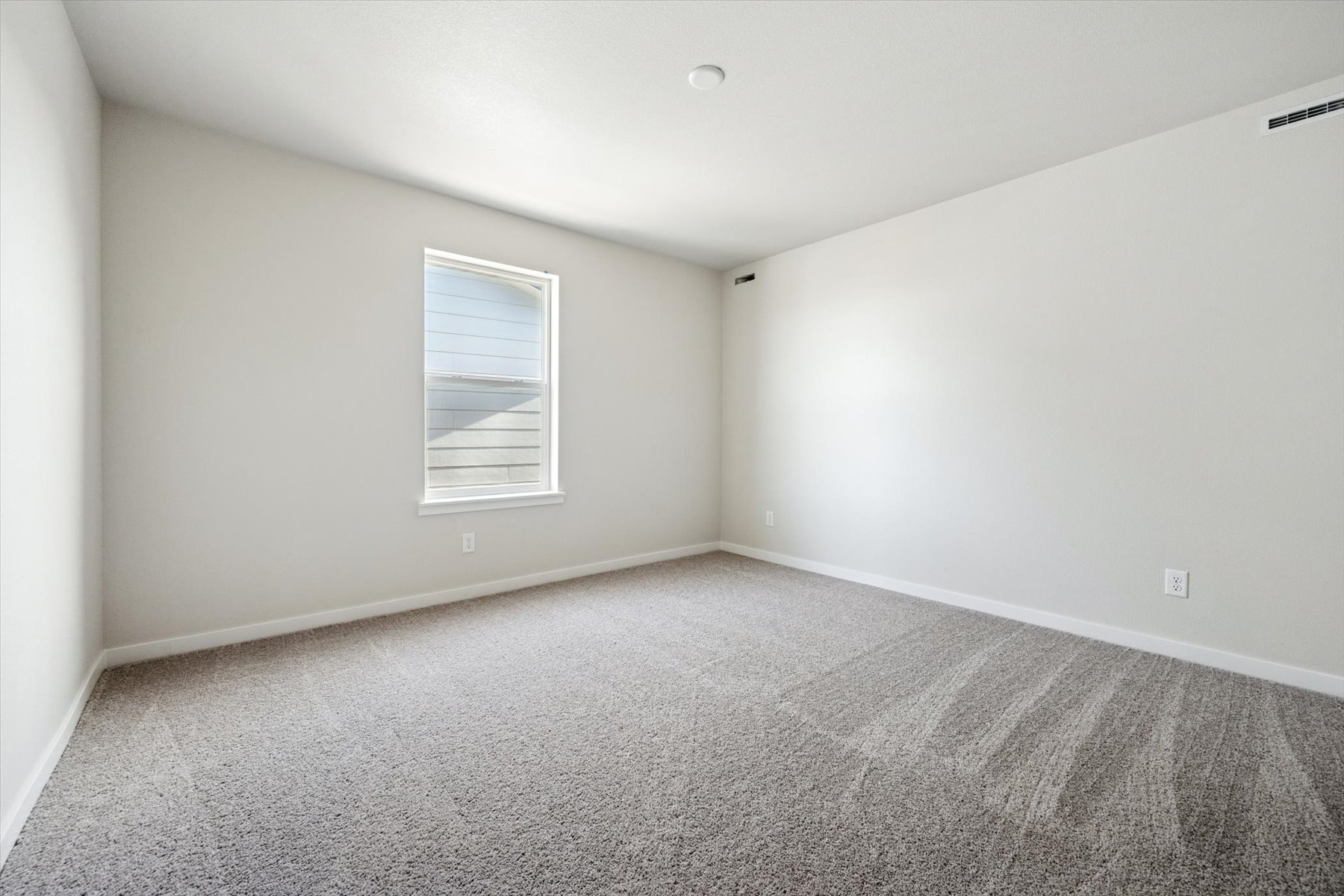 A room with a carpet and a window.