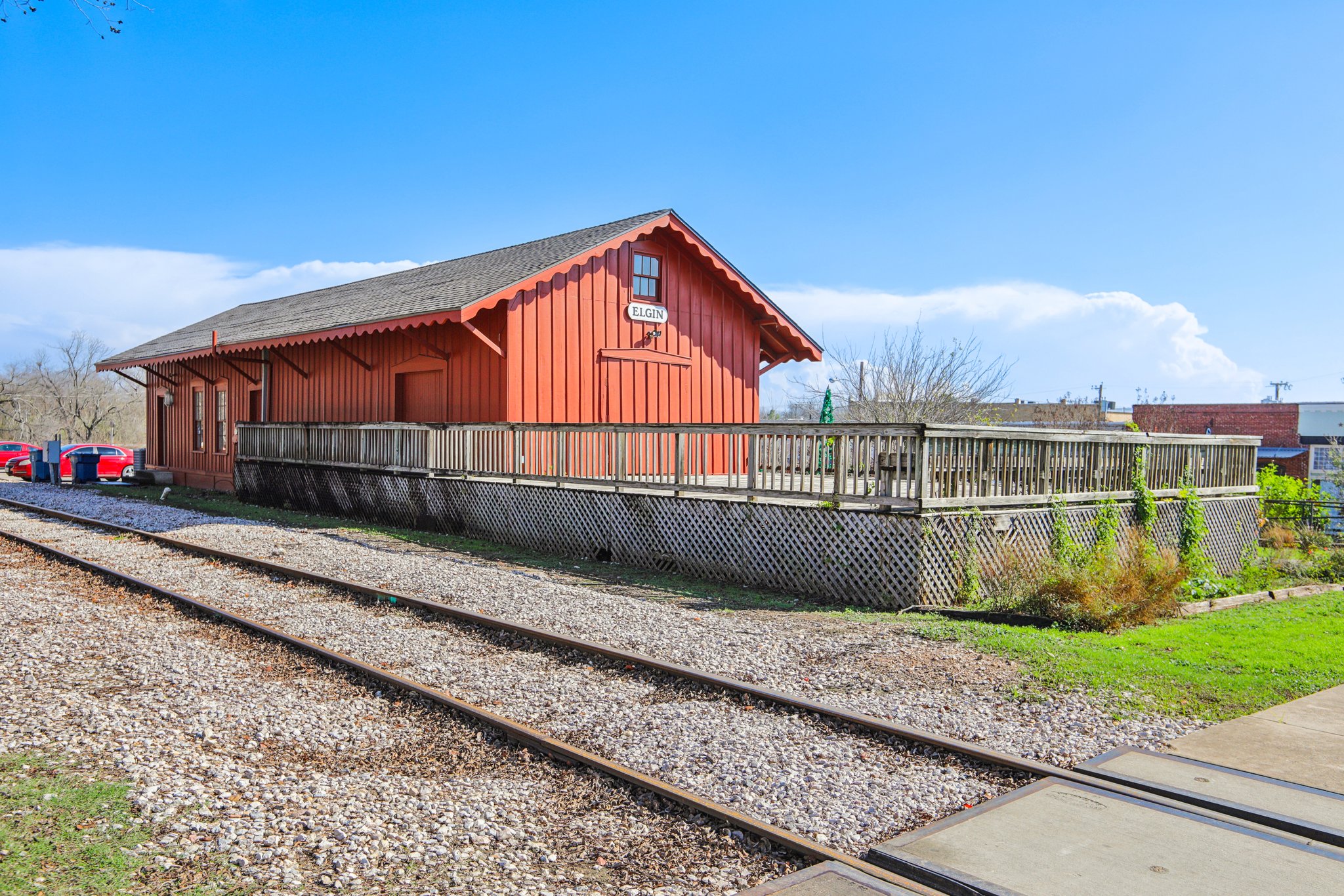 A train station with a red barn.
