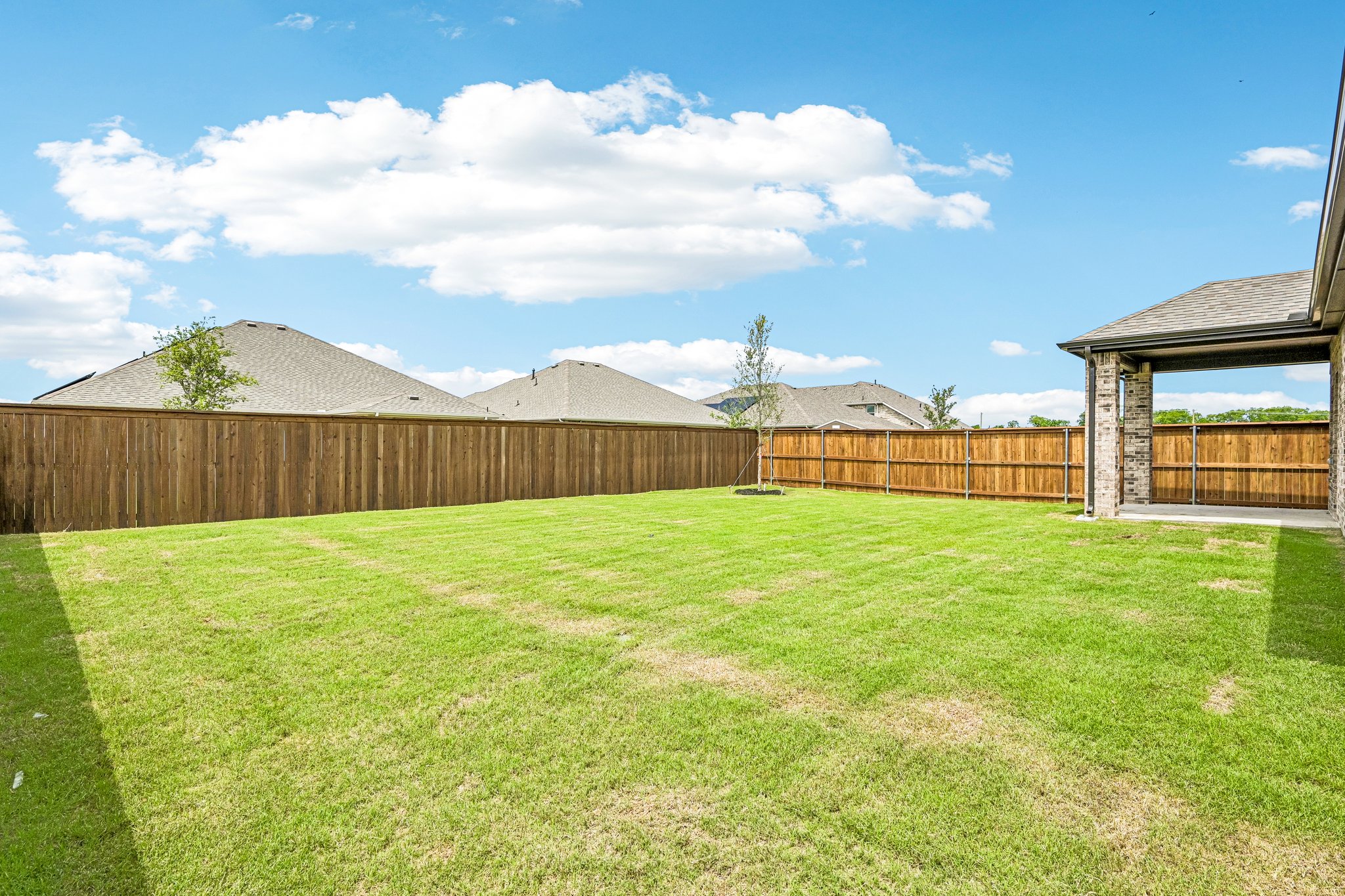 A fenced in yard with a house and mountains in the background.