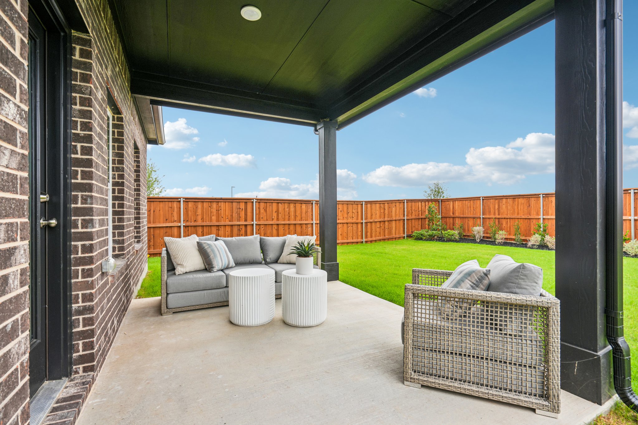 A patio with a white couch and a white table and a white basket.