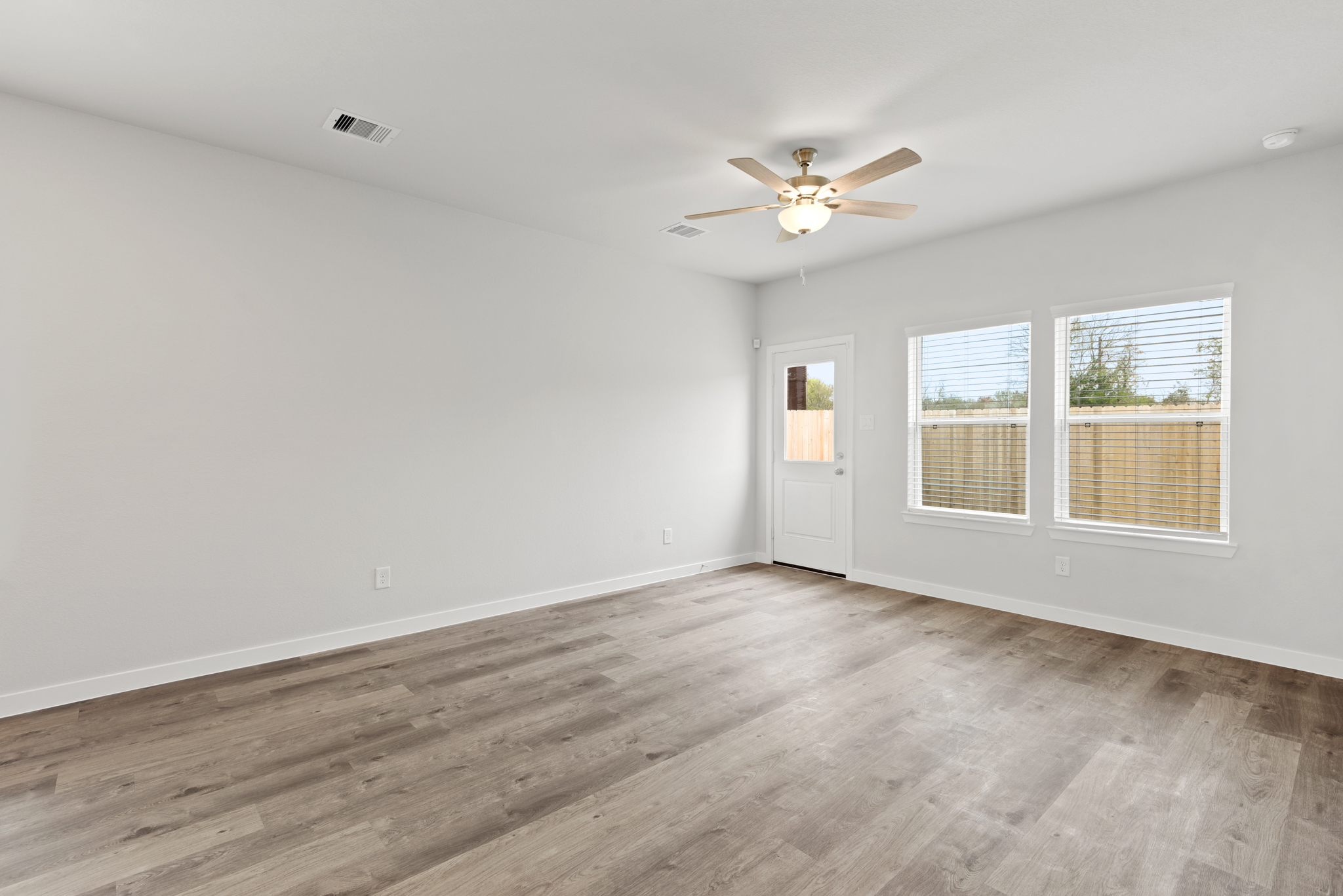 A room with a ceiling fan and a wood floor.