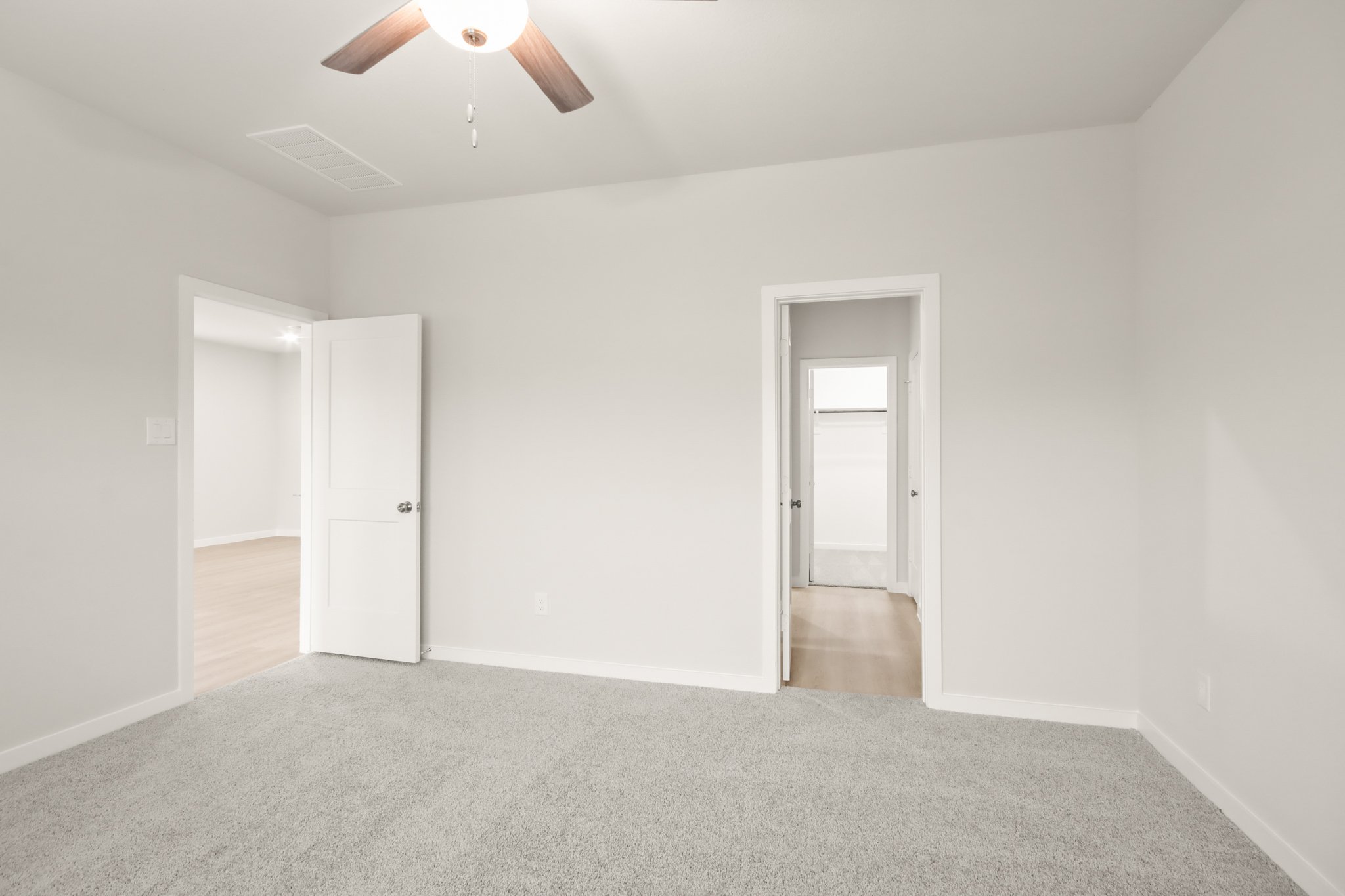 A room with a ceiling fan and a door.