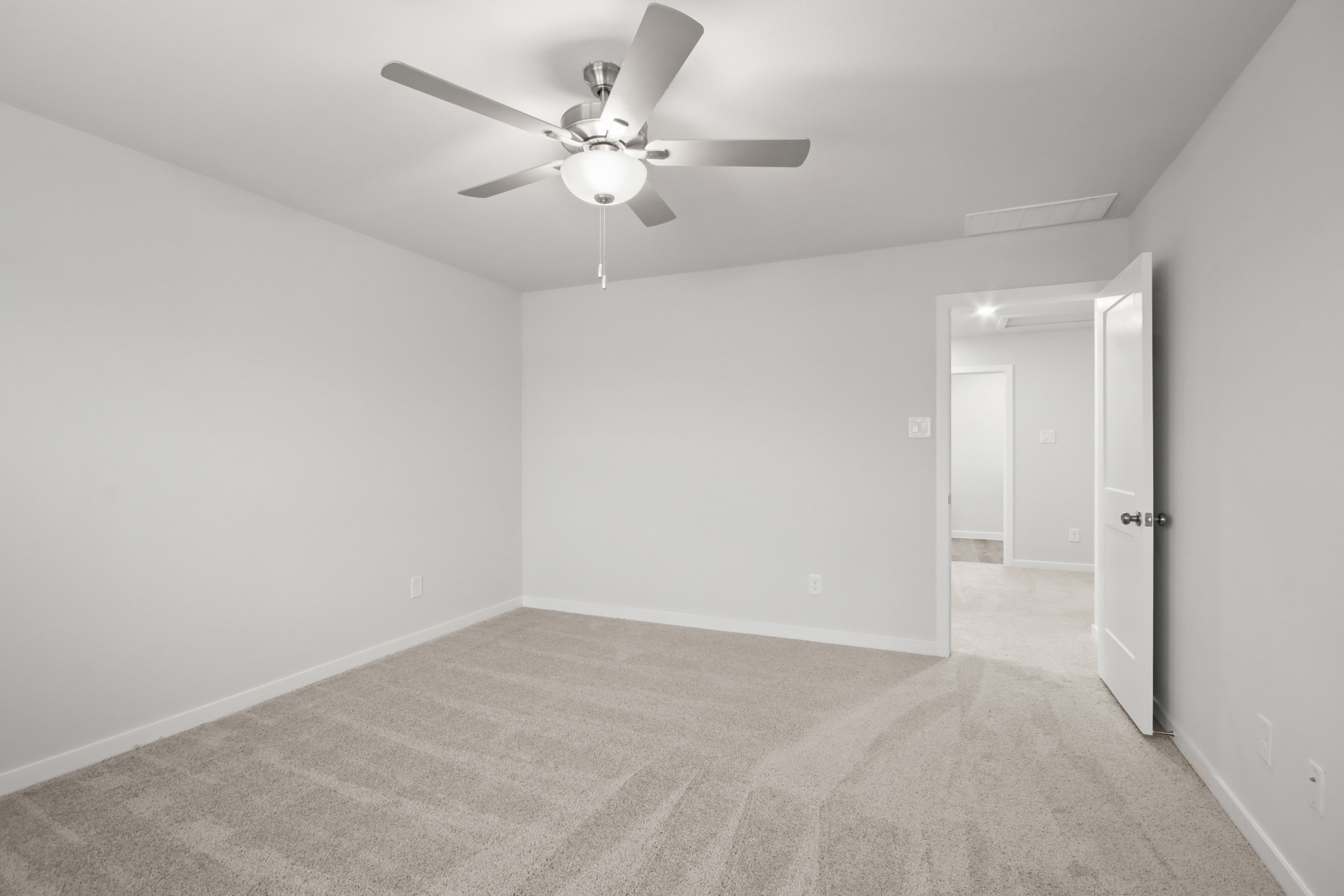 A room with a ceiling fan and a carpet.