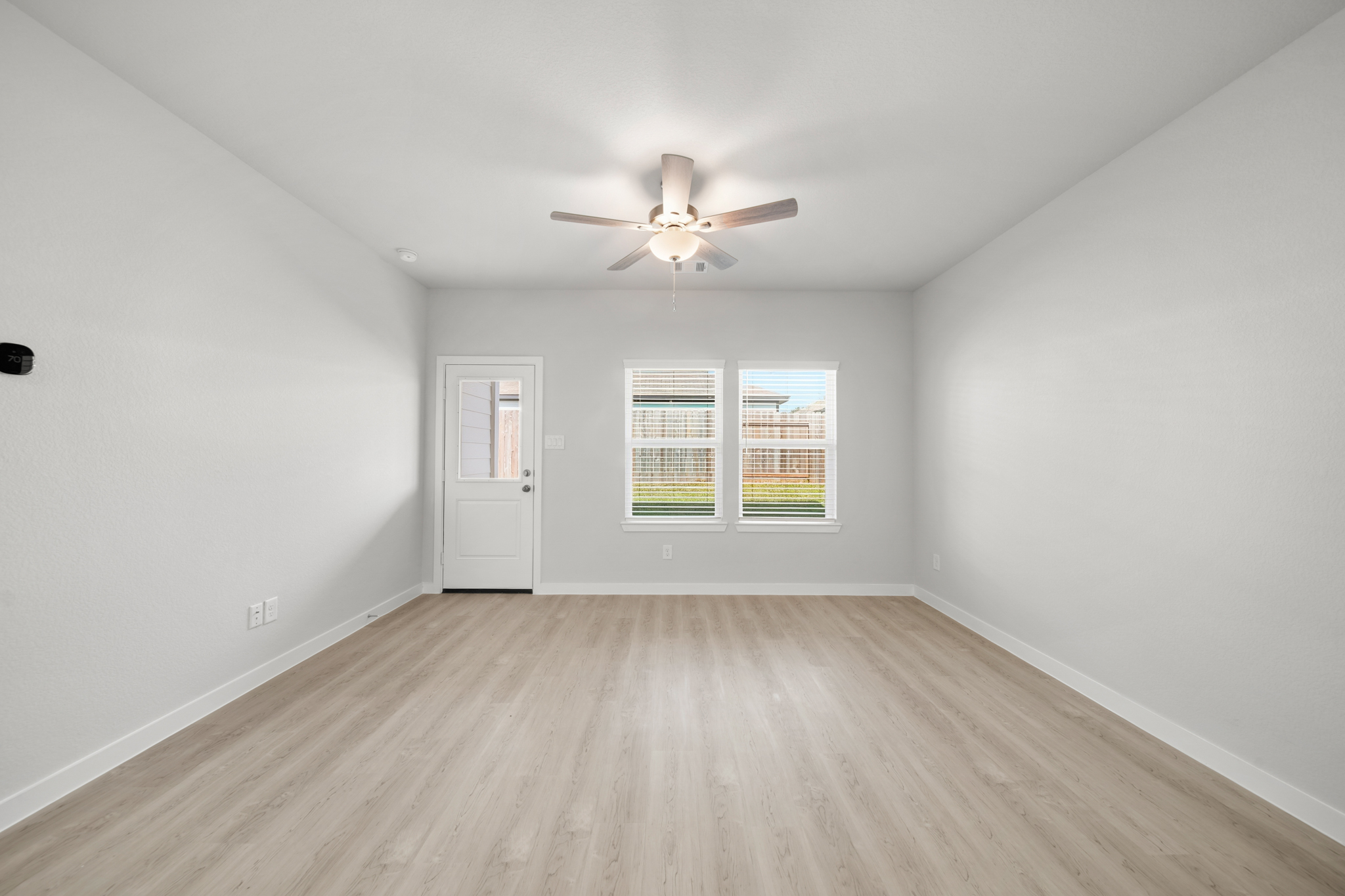 A room with a ceiling fan and a wood floor.