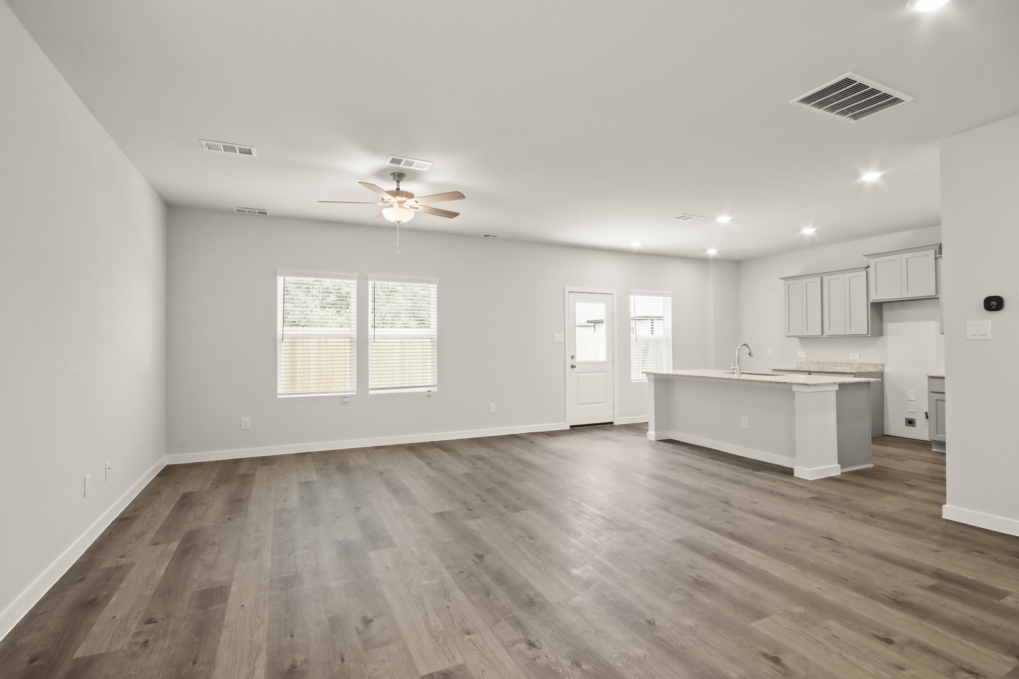 A large empty room with a wood floor and a white counter top.
