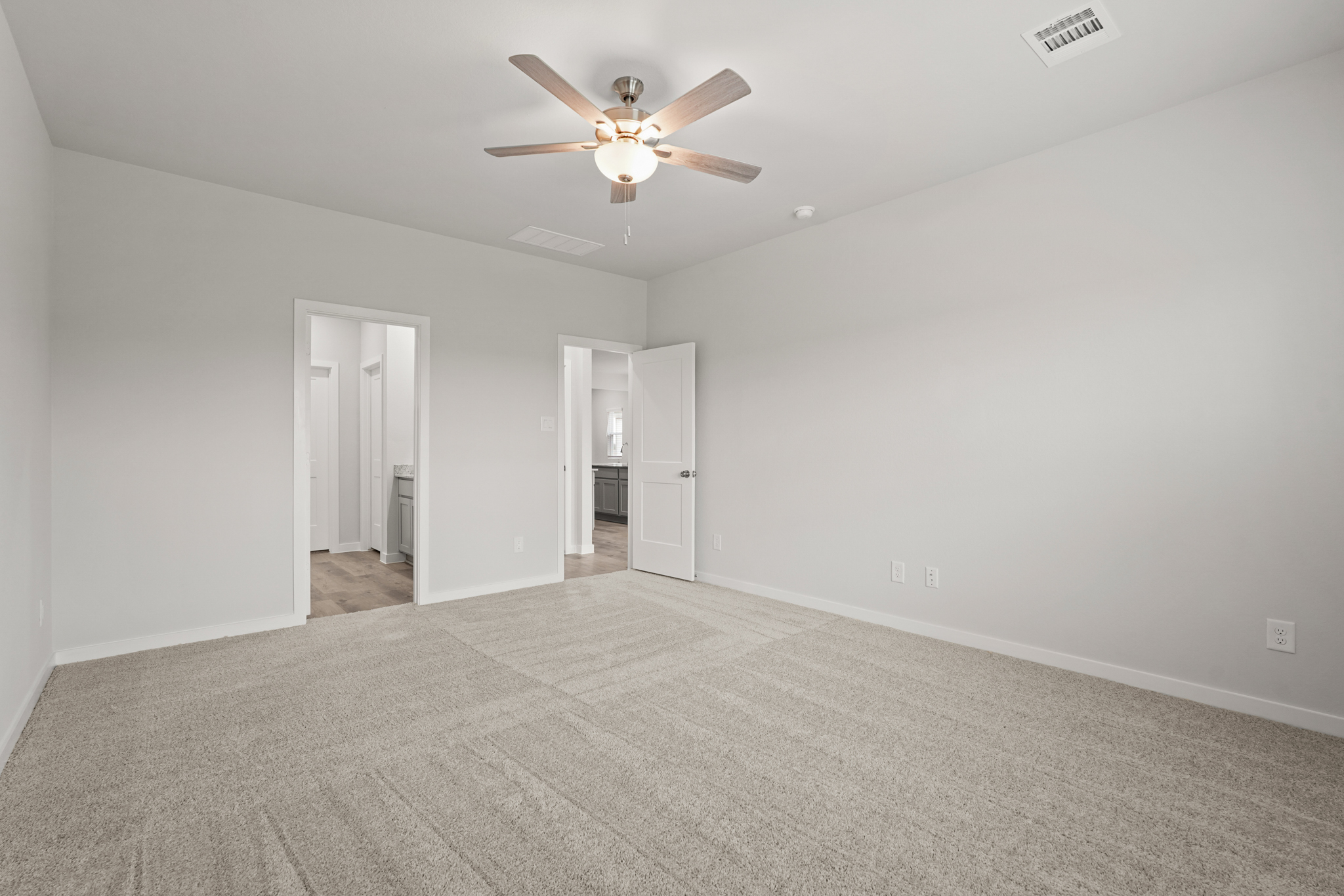 A room with a ceiling fan and a carpet.