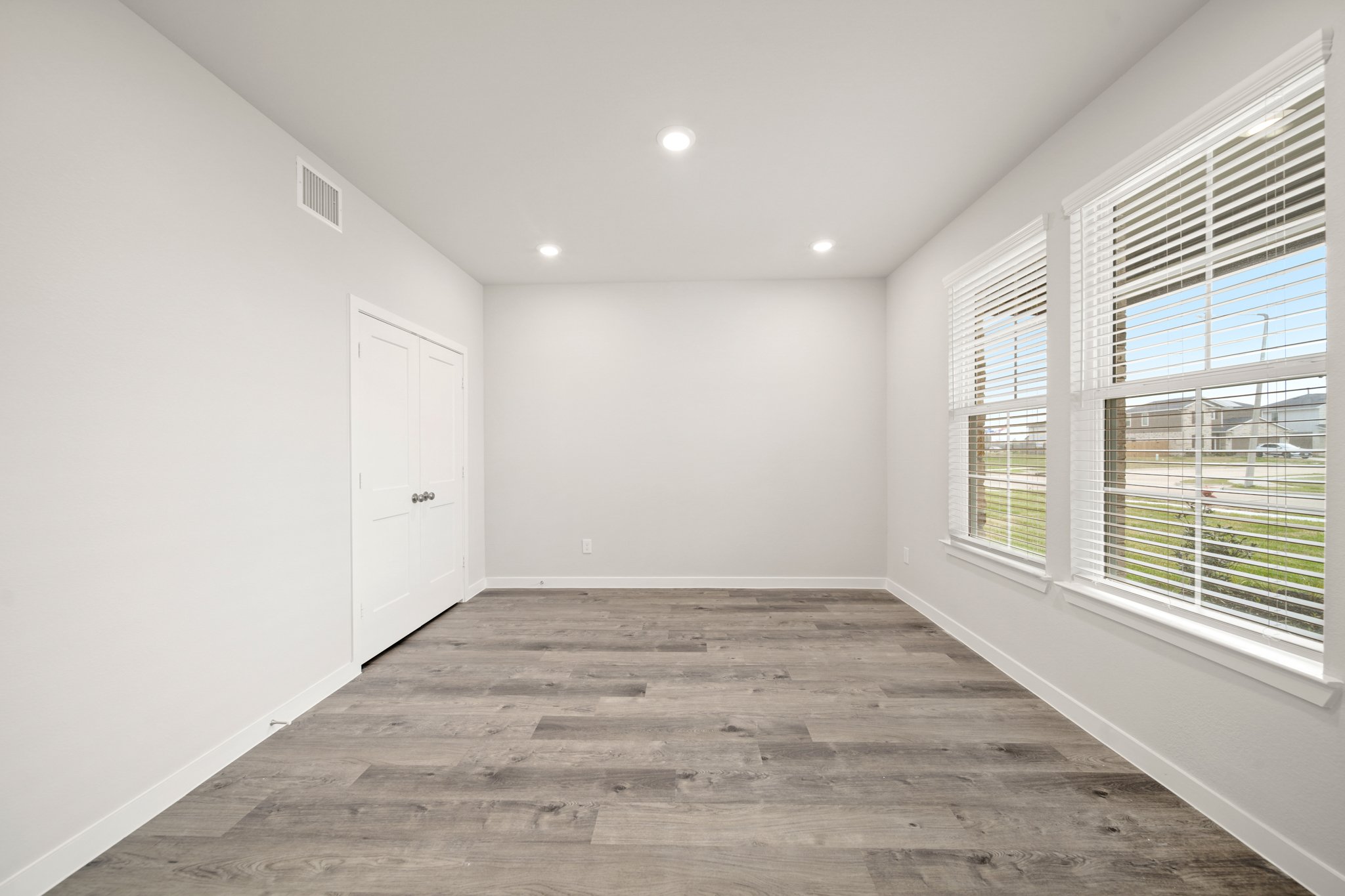 A room with windows and a wood floor.