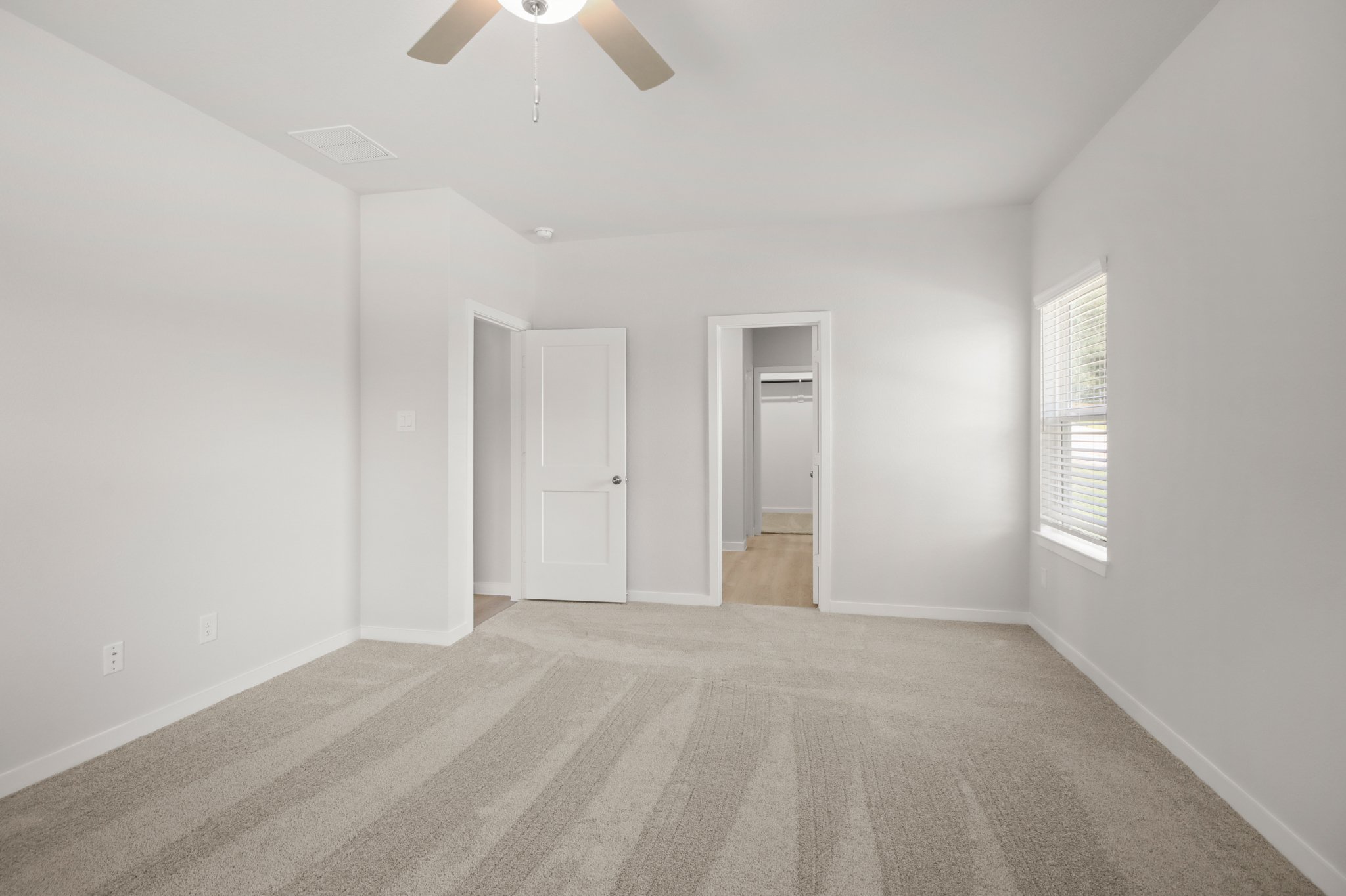 A room with a ceiling fan and a door.