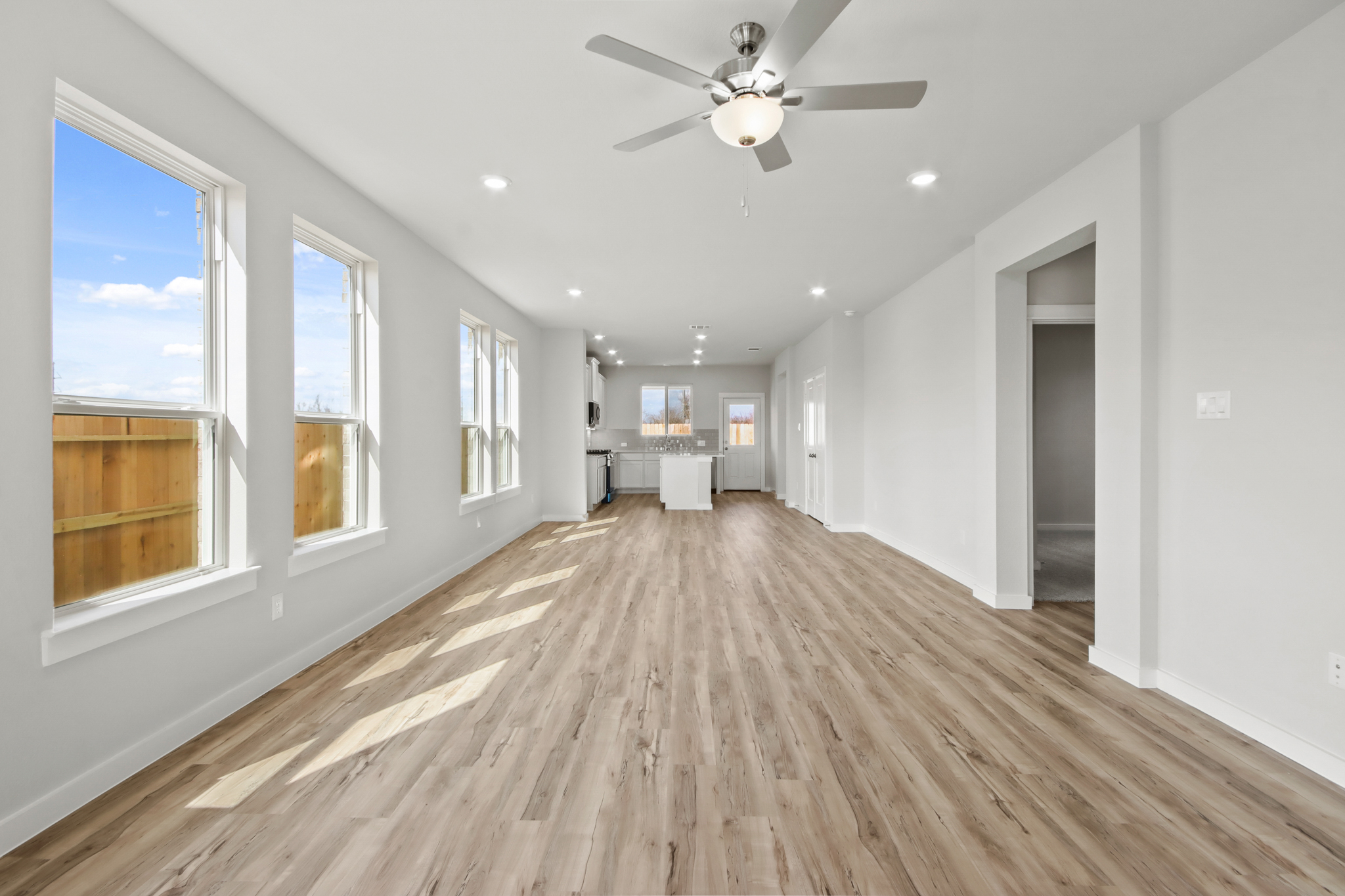 A large room with a wood floor and a ceiling fan.