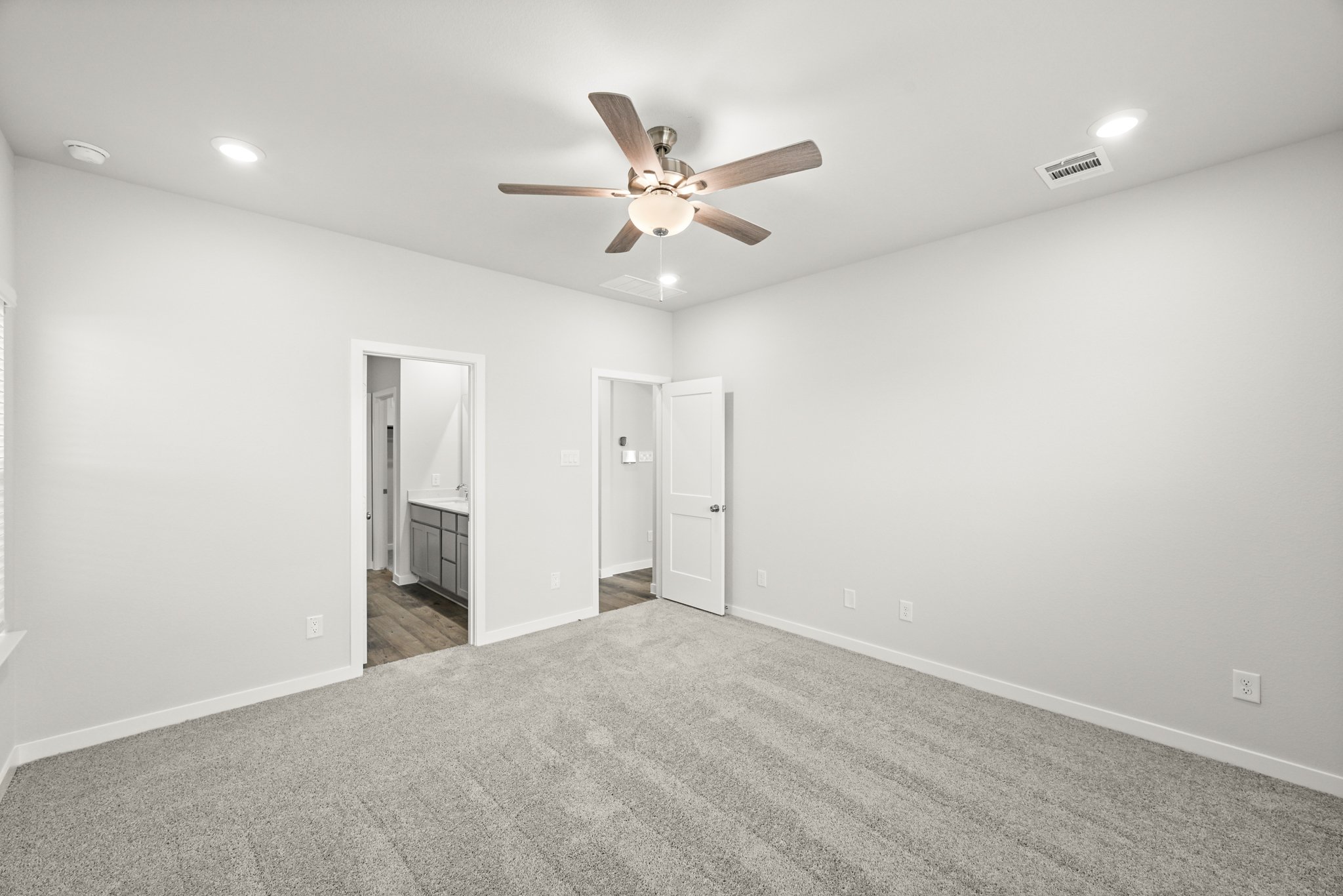 A room with a ceiling fan and a carpet.
