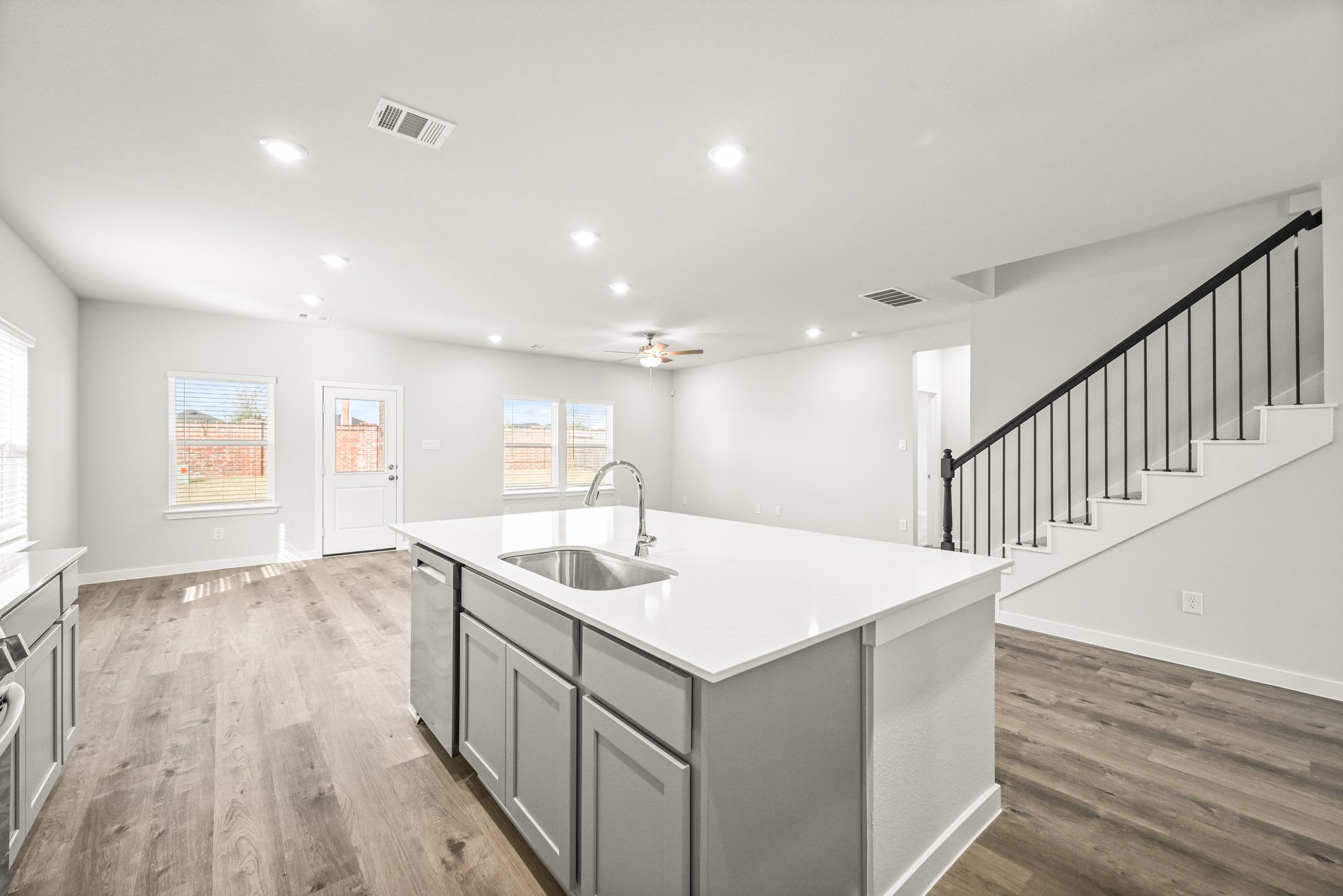 A kitchen with a large white countertop and a wood floor.