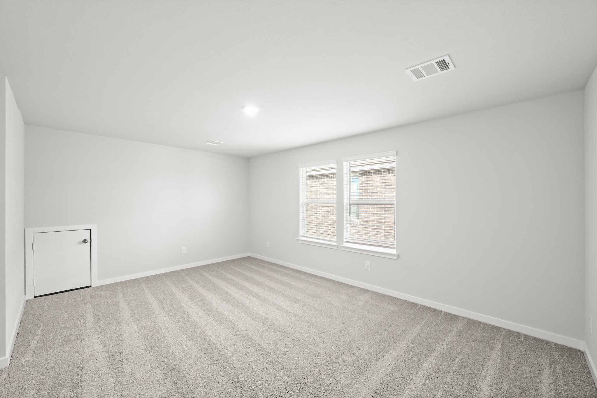 A room with a carpet and a white wall.