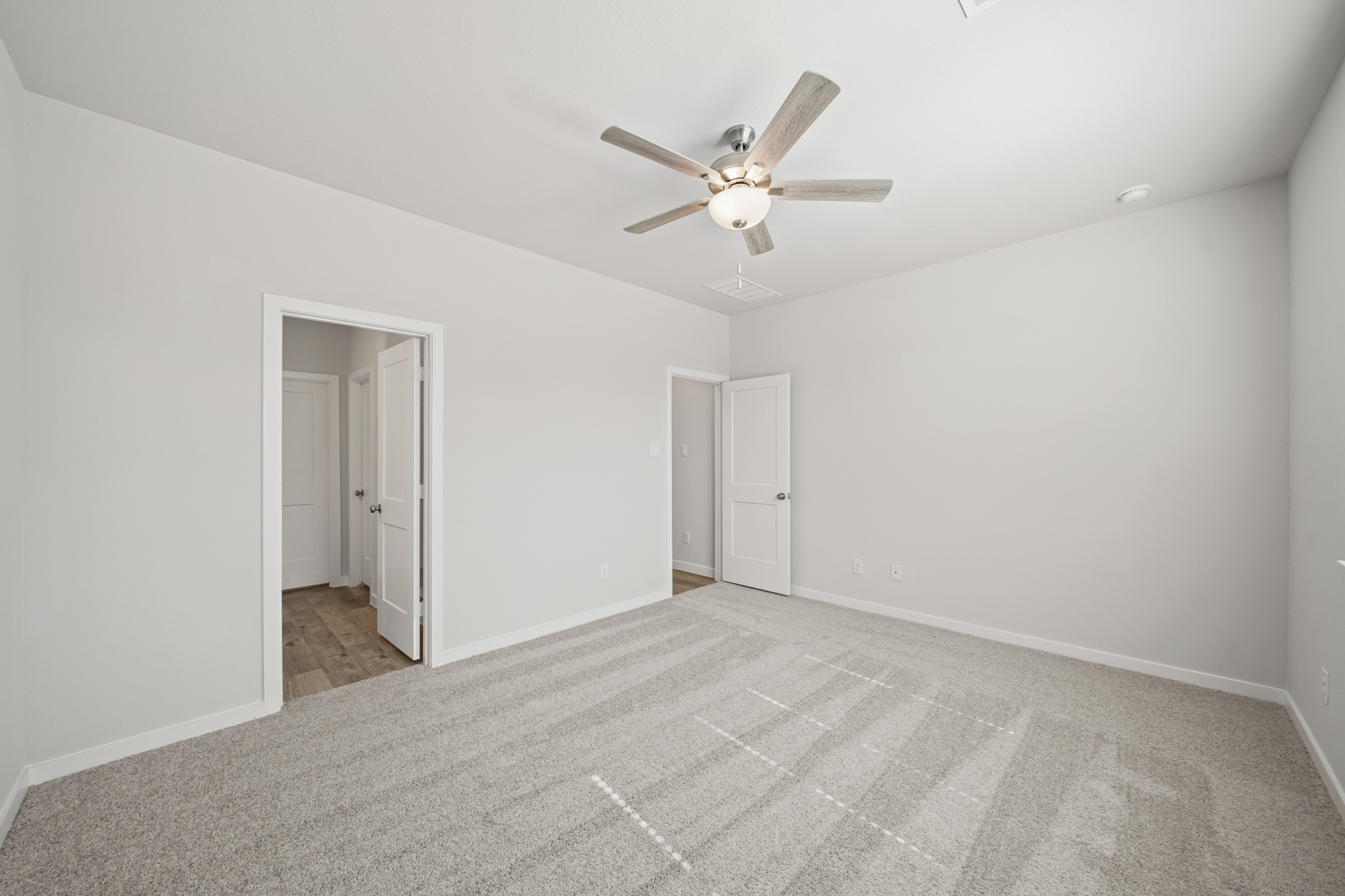 A room with a ceiling fan and white walls.