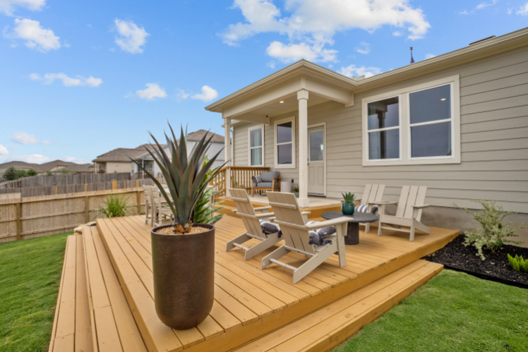A deck with chairs and a table on it next to a house.