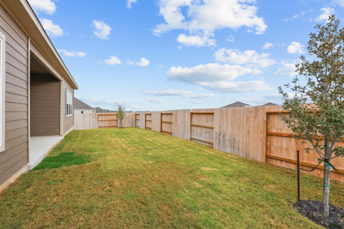 A fenced in yard with a tree and a house.
