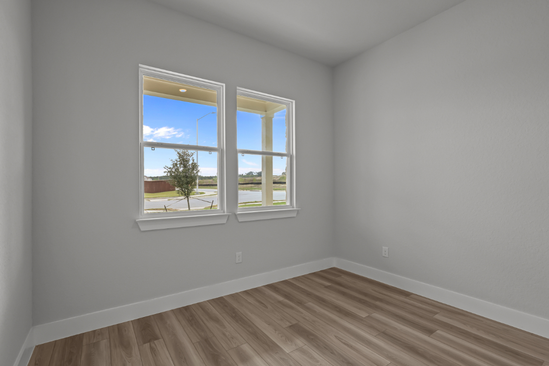 A room with a wood floor and a window with a view of the ocean.
